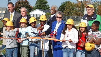 DelDOT's Assistant Director of Planning, Joe Cantalupo (left) gets help cutting the ribbon from H.O. Brittingham Students, local officials, and residents.
