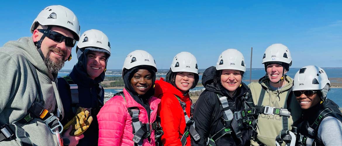 A group of people with helmets and safety harnesses as doing some type of ariel work